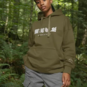 Geometry of the Wild Military Green Hoodie by NOWFIELD porté dans un paysage naturel, illustrant l'esprit outdoor et minimaliste de la collection.